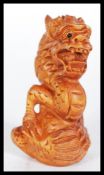 A 20th Century carved Japanese netsuke in the form of a dragon being signed to base. Measures 6 cm
