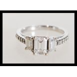 A hallmarked 9ct white gold three stone ring having three emerald cut white stones with brilliant