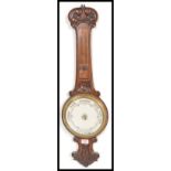 An early 20th Century Aneroid barometer set within a wooden case with carved floral decoration and