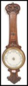 An early 20th Century Aneroid barometer set within a wooden case with carved floral decoration and