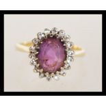 An 18ct gold diamond and amethyst ring having a large central faceted purple stone with a halo of