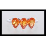 A hallmarked 9ct white gold three stone ring having three prong set faceted orange stones. Weighs