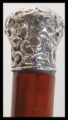 A malacca walking stick having a silver hallmarked knop to the top with scrolled floral decoration
