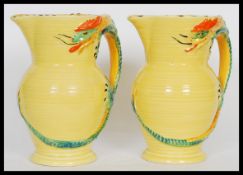 A pair of early 20th Century Burleigh Ware Art Deco water jugs having relief dragon handles. Stamped