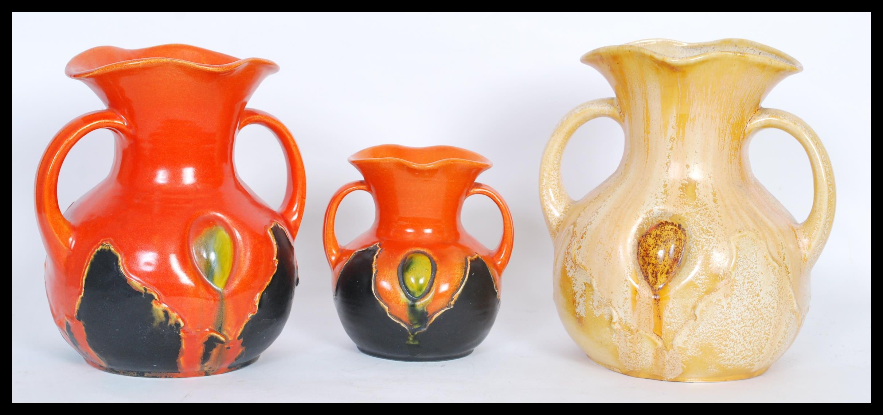 A group of three early 20th Century twin handled vases of bulbous form having flared rims,