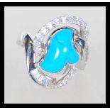 A sterling silver turquoise set dress ring  having a halo of brilliant and baguette cut CZ stones.