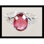 A hallmarked 18ct white gold ring prong set with an oval cut Rubellite flanked by two small white
