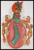 An antique style cast metal Armorial coat of arms / Heraldic crest depicting an embowed arm in armor