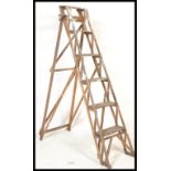 A vintage early 20th Century lattice framed wood Industrial folding step ladder. The six tread