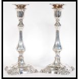 A pair of silver candlesticks raised on stepped square bases with scrolls with bulbous stem and