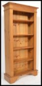 An antique style country pine large tall bookcase cabinet raised on bracket feet with a set of