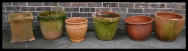 A collection of vintage terracotta stone garden planters of various sizes and forms including