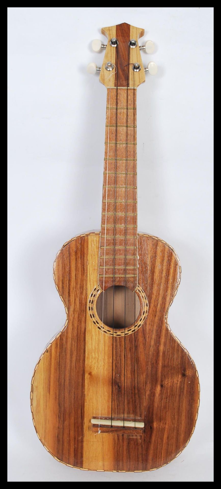 A scratch built Ukulele having inlaid dark wood in a checker board pattern to the sound hole and