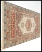 A 20th Century Persian Islamic rug having a red ground with a beige main border with geometric