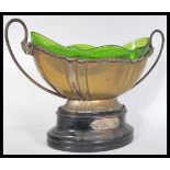 An early 20th Century twin handled silver plated EPNS trophy with green glass liner, raised on