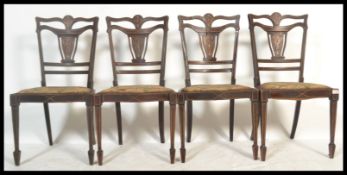 A set of four Edwardian marquetry seaweed inlaid mahogany dining chairs being raised on square