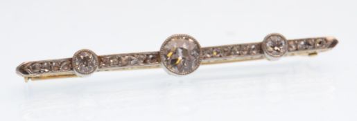 An early 20th century gold and diamond bar brooch. The brooch being set with three bezel set round
