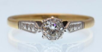 An 18ct gold and platinum single stone solitaire diamond ring having diamond set shoulders.