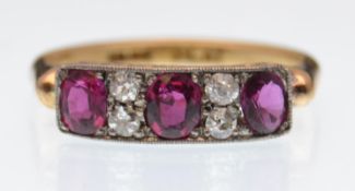 An 18ct gold ruby and diamond ring. The ring being set with three oval cut rubies interspaced with