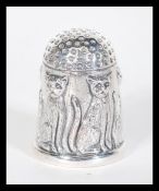 A sterling silver thimble having relief decoration