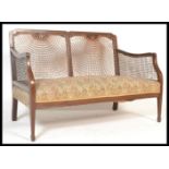 A Georgian revival mahogany framed bergere two seat sofa, fan back weave to the back and sides