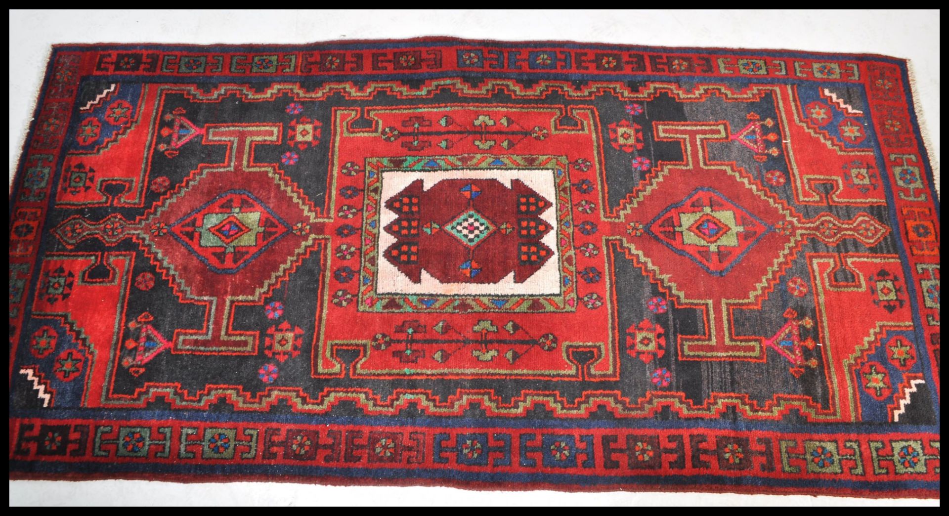 A Persian Islamic tribal Bakhtiari hand made wool rug / floor carpet having a red ground with