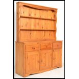 A 20th Century pine dresser having an arrangement of drawers and cupboards underneath plate rack