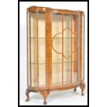 A 20th Century curved glass display cabinet raised on cabriole legs having bevelled glass sides. The