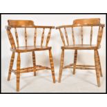 A pair of Victorian beech and elm wood smokers bow armchairs being raised on ring turned legs united