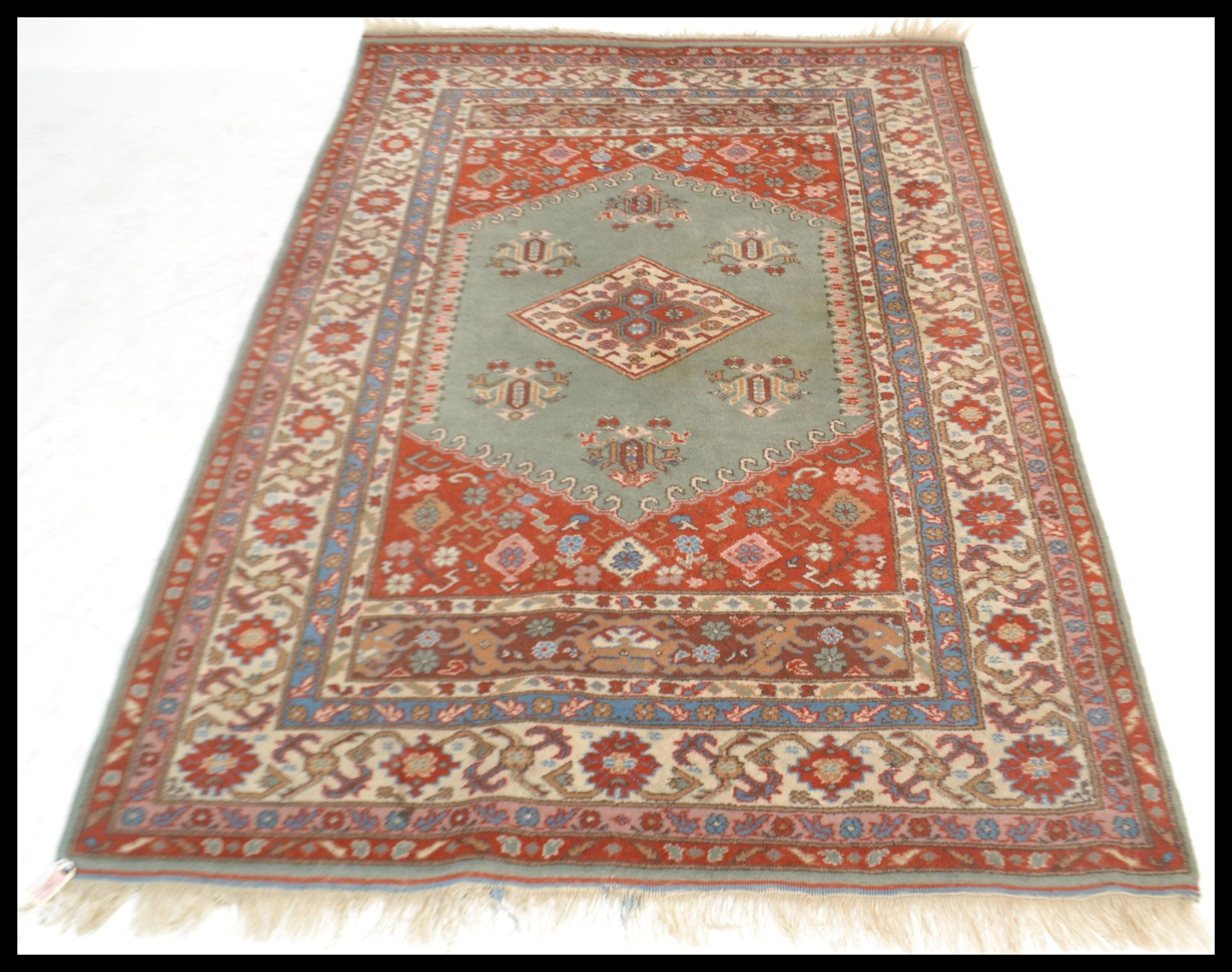 A 20th Century Persian Islamic rug having a red gr