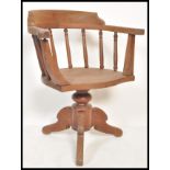 An early 20th Century Edwardian oak captains chair raised on quadruped base with turned rail