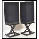 A pair of retro KEF speakers in black finish on ebonised floor stands.