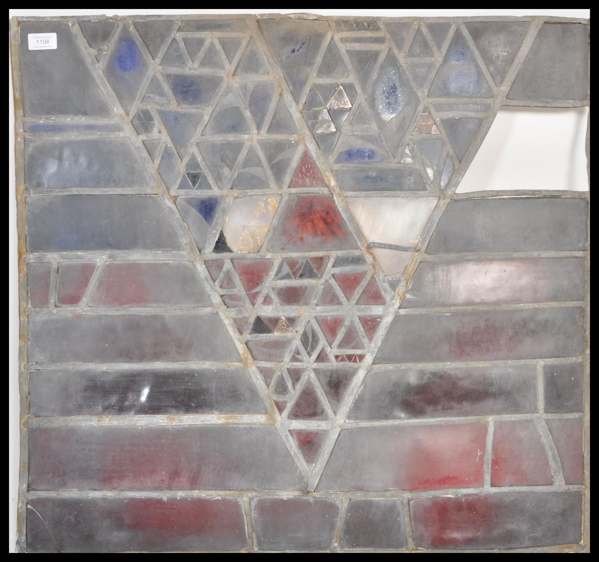 An early 20th Century leaded stain glass window having a geometric triangular design made up of