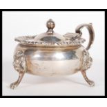 An early 20th Century hallmarked silver large lidded mustard pot raised on lion mask paw feet with