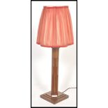 A 1930's Art Deco oak table lamp being raised on a square base with shaped column and shade atop.