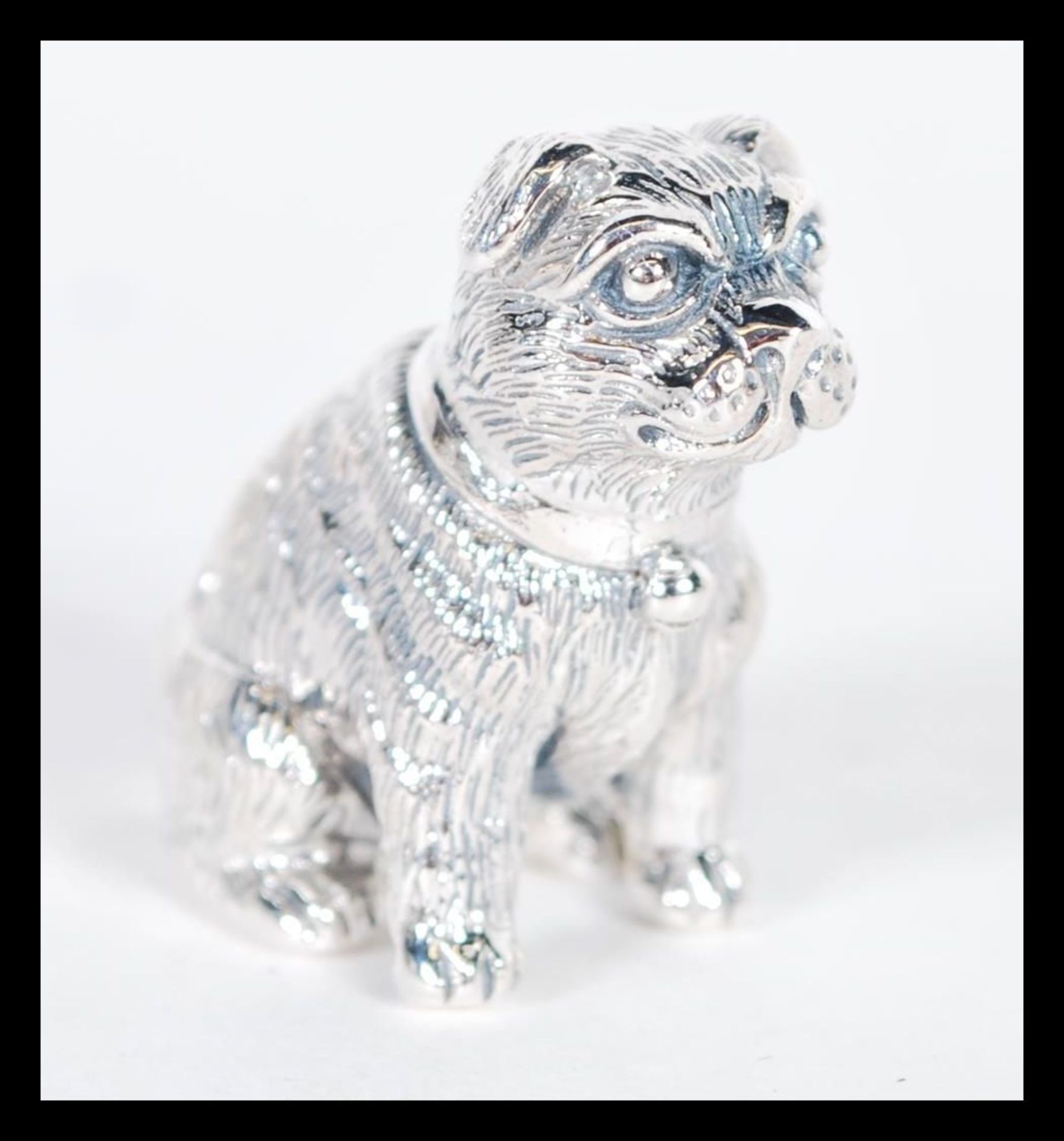 A sterling silver figurine in the form of a dog modelled in a seated position. Weighs 19 grams.