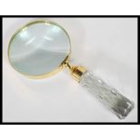 A large brass cased magnifying glass having a faceted glass tapering handle.