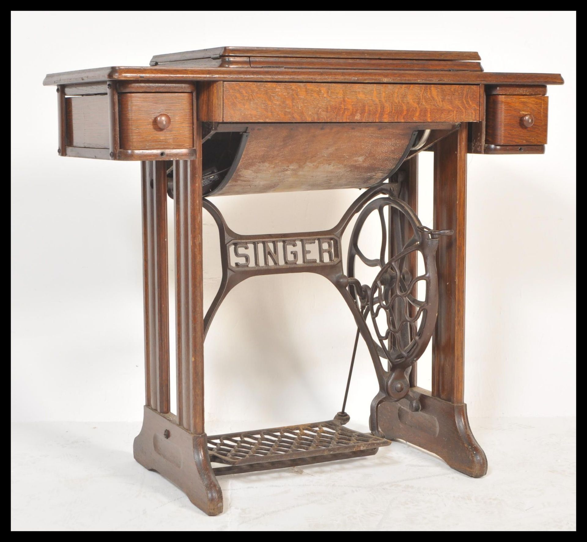 A 1930's Art Deco oak Singer sewing machine table. The electric Singer machine set to a stunning