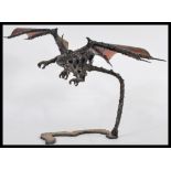 A cast metal sculpture of an armoured dragon in flight in the the gothic taste raised on a