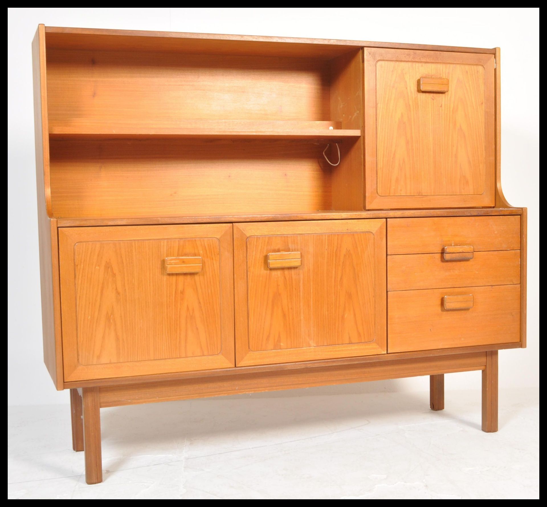 A retro 20th Century teak wood highboard sideboard credenza by Alfred Cox having an arrangement of