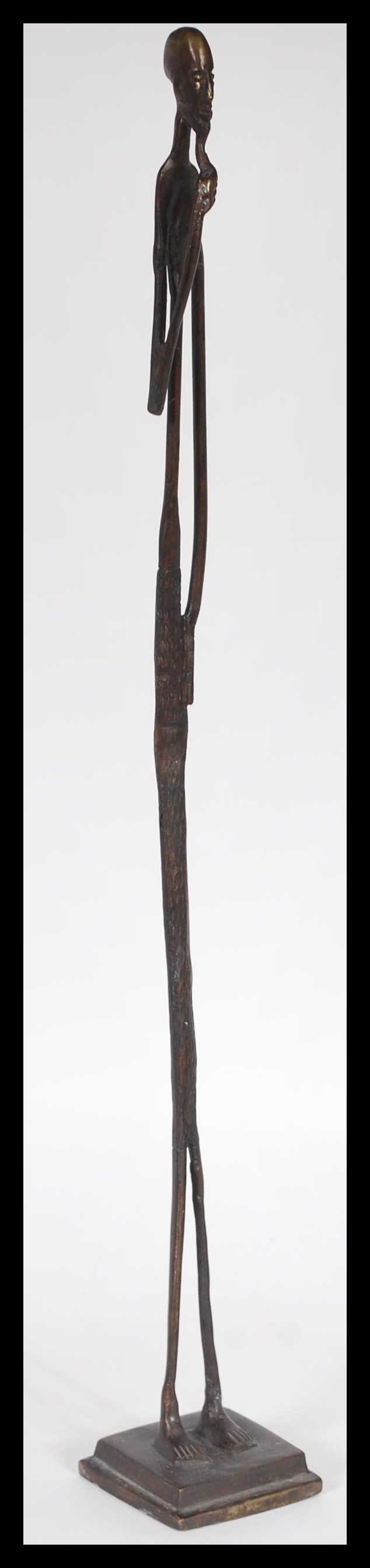 An African tribal bronze figurine of an elongated man stroking his beard raised on square base. 52cm