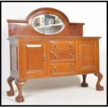 An Edwardian mahogany mirror back sideboard dresser being raised on claw and ball feet with a