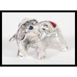A sterling silver pin cushion in the form of an elephant having red baize pin cusion to top.