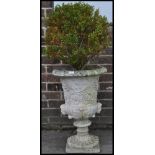 A antique garden reconstituted stone plant pot in a shape of urn, having flower details and square