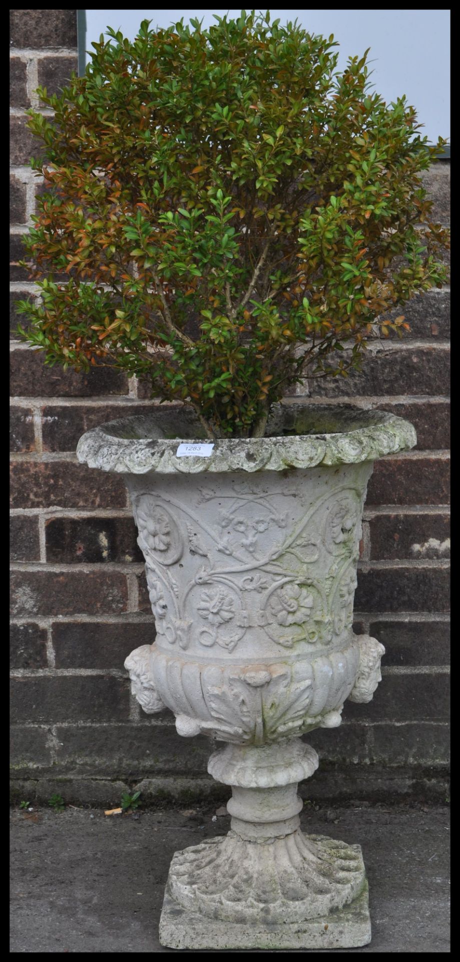 A antique garden reconstituted stone plant pot in a shape of urn, having flower details and square