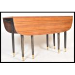 A 1970's G-Plan tola wood retro drop leaf dining table, the legs raised on ebonised turned legs with