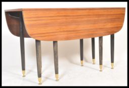 A 1970's G-Plan tola wood retro drop leaf dining table, the legs raised on ebonised turned legs with