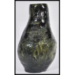 A 20th Century studio pottery heavy lamp base having a green glaze with incised decoration depicting