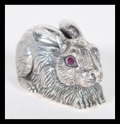 A sterling silver figurine in the form of a rabbit or hare having faceted red stone eyes. Weighs