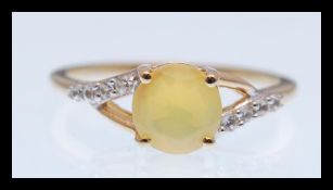 A hallmarked 9ct gold ring prong set with a brilliant cut yellow opalescent stone having a split